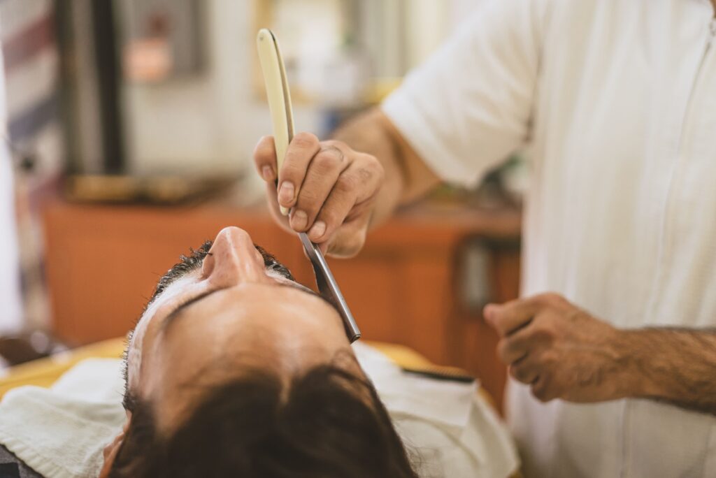 Barber wykonujący tradycyjne golenie brzytwą w salonie barberskim