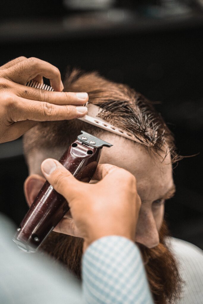 Barber strzygący włosy mężczyzny w profesjonalnym salonie barberskim