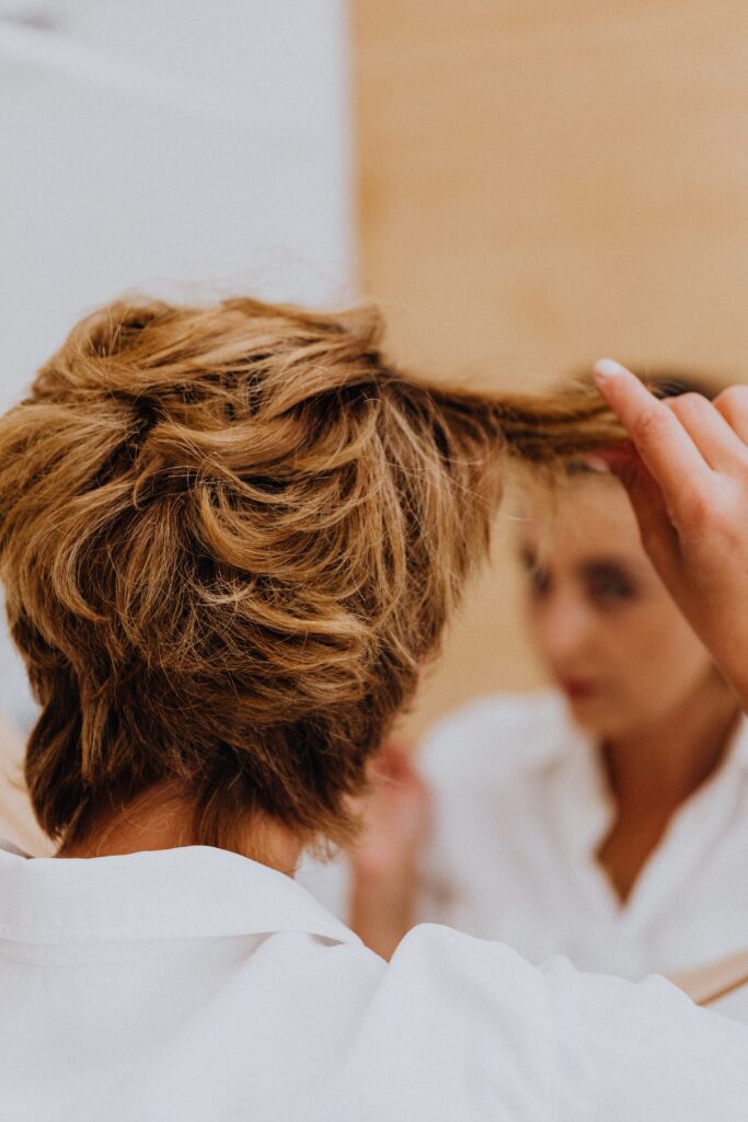 close up woman or man looking at shiny dark natural hair color in mirror